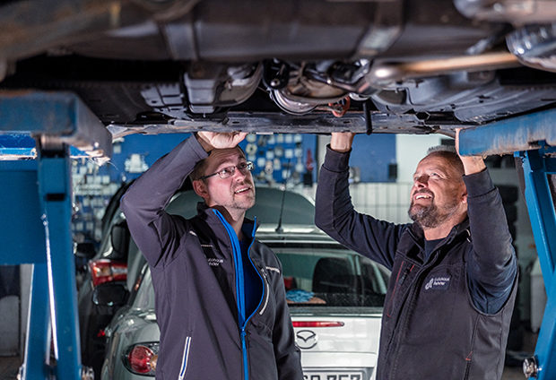 Zwei Mechaniker sehen sich ein Auto von unten an